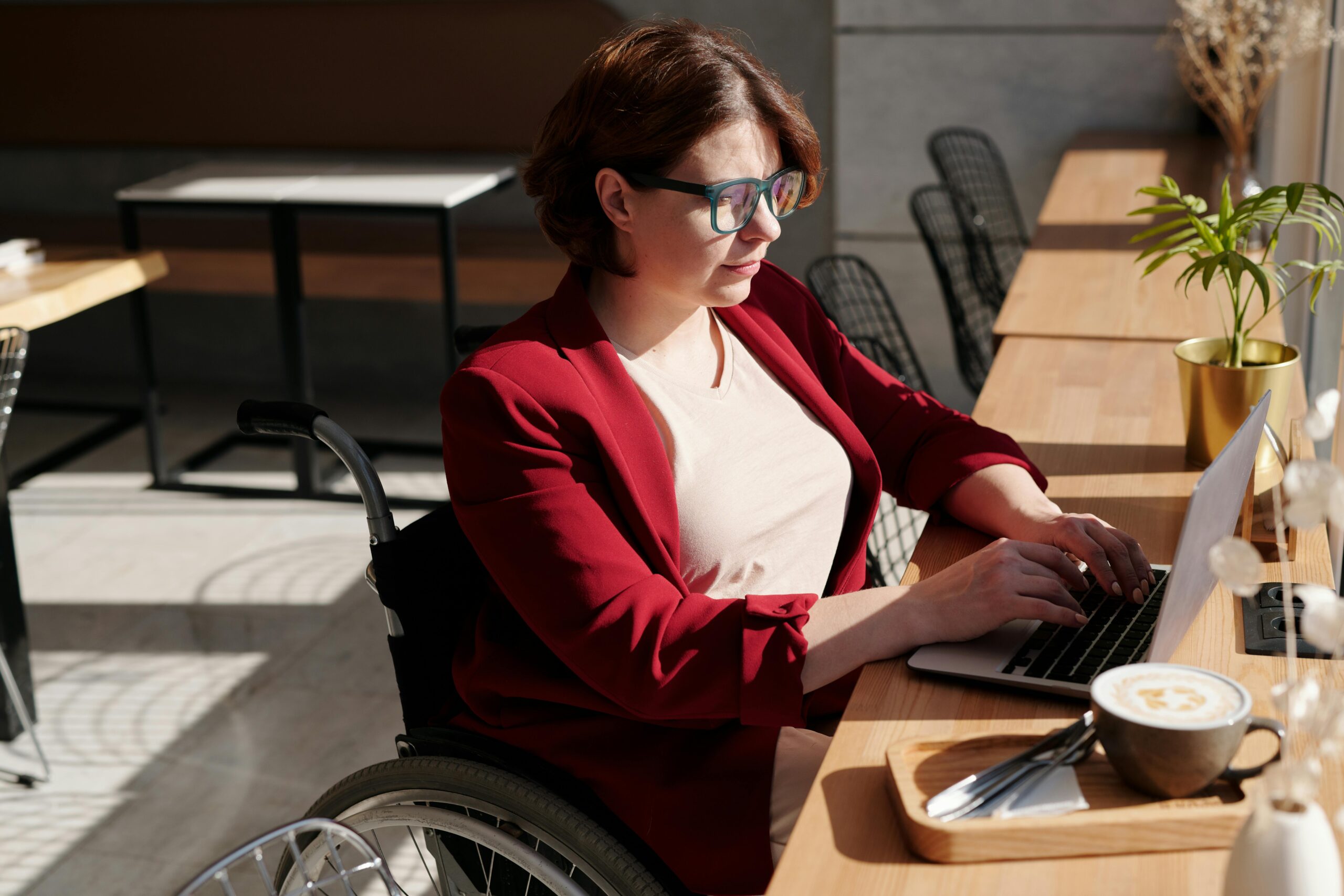 1. A woman in a wheelchair focused on her laptop, engaged in work or communication.